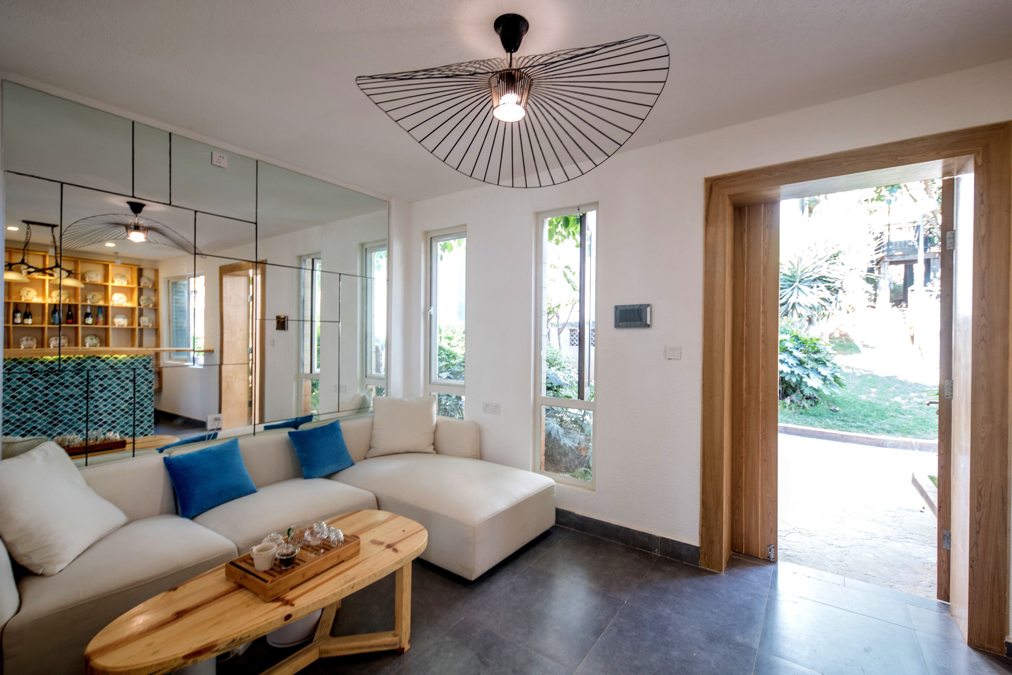 A modern living room with a sectional sofa, a wooden coffee table, and a unique ceiling light fixture.