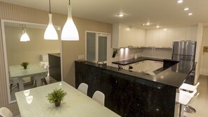 Una cocina moderna con armarios blancos, una isla de mármol negro y electrodomésticos de acero inoxidable.