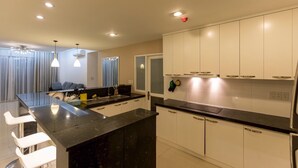 Una cocina moderna con armarios blancos, encimera negra e iluminación colgante.