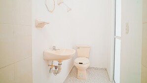 Ein kleines Badezimmer mit Waschbecken, Toilette und Spiegel.