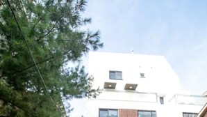 A narrow alley with two people walking towards a modern building with multiple windows and a garage. - Kuki House (Seoul)