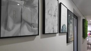 A hallway with framed artwork on the wall, including a piece with the text "Love you" and another with a mountain landscape. - Kuki House (Seoul)