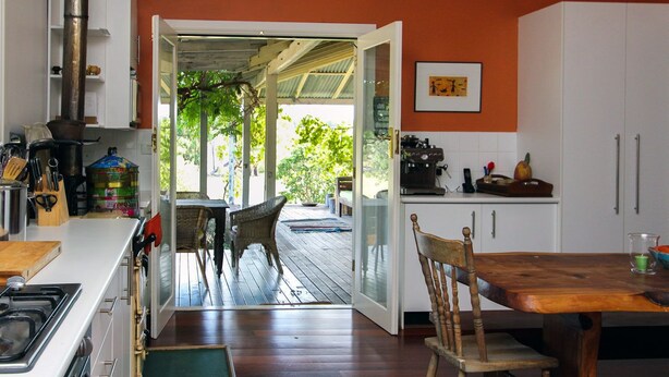 A kitchen with a dining area, a stove, and a coffee machine. - Lone Pine Farmhouse (Meroo)