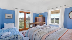 A bedroom with two beds, a wooden dresser, and a view of the outdoors. - Lone Pine Farmhouse (Meroo)