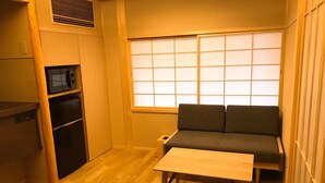 A compact room with a sofa, a small table, a microwave, and a refrigerator. - Shiki Shiki Ponto (Kyoto)