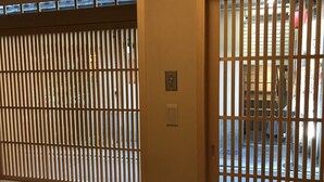 A room with a sliding door featuring vertical blinds, a light switch, and a power outlet on the wall. - Shiki Shiki Ponto (Kyoto)