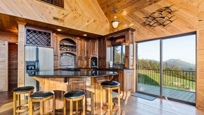 Eine moderne Küche mit Holzschränken, einem Edelstahlkühlschrank, einem eingebauten Backofen und einer großen Kochinsel mit Barhocker.