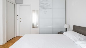Une chambre à coucher comprenant un lit, une table de chevet, une lampe, une armoire et une porte.