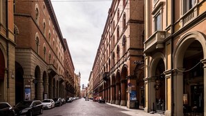 Une rue pavée bordée de bâtiments historiques dotés d’arcs en plein cintre et de balcons.