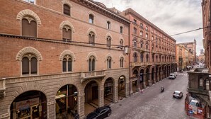 Une vue de rue d’un bâtiment historique doté de fenêtres en arc de cercle et d’une rangée de boutiques au rez-de-chaussée.