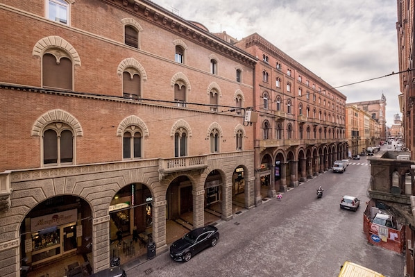 A street view of a historic building with arched windows and a row of shops on the ground floor. - Cavalieri's Grand (Bologna)