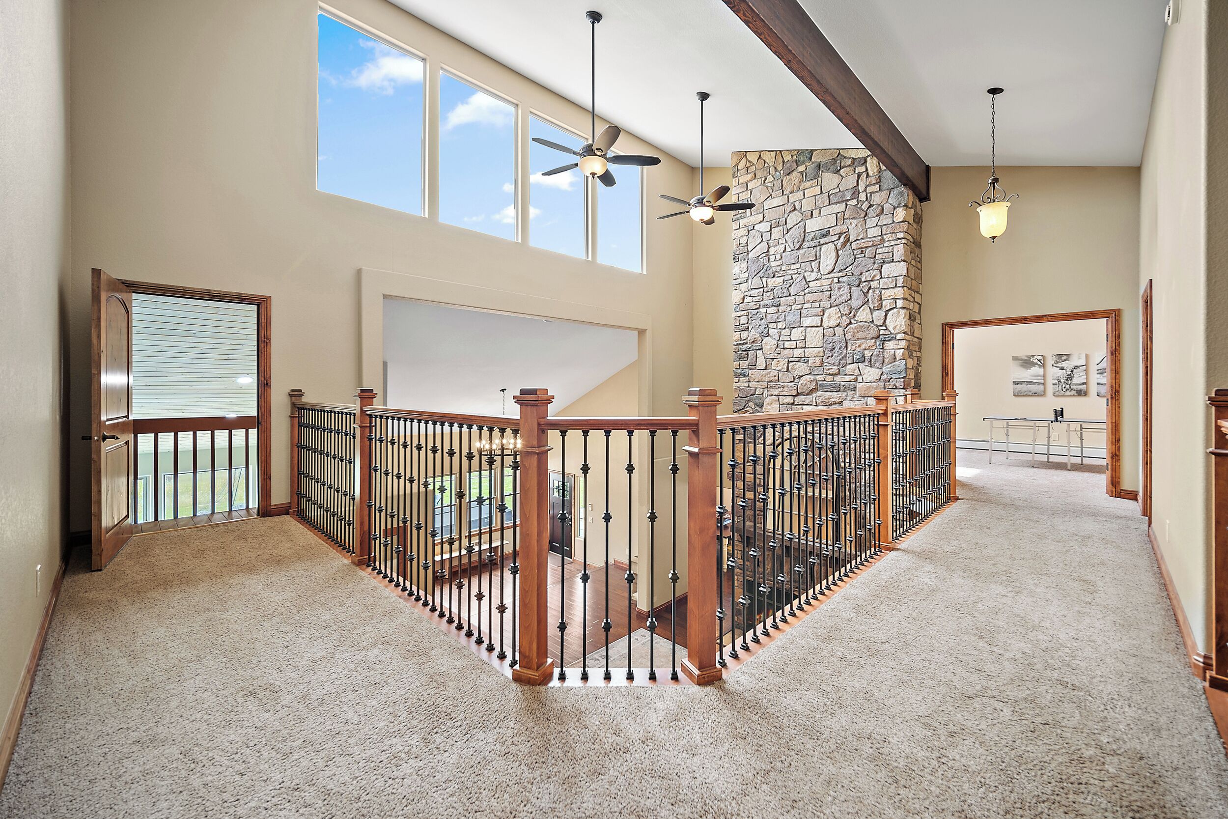 A spacious interior with a high ceiling, a stone wall, and a wooden railing.
