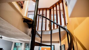 A spiral staircase with wooden railings and a metal handrail. - Stylish Dog-Friendly Condo - West End on Comm St (Provincetown)
