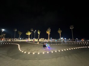 An outdoor area with a paved surface, palm trees, and a circular arrangement of lights. - Cozzy Seaview Apartment (Ho Chi Minh City)