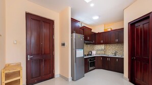 A kitchen with dark wooden cabinets, a stainless steel refrigerator, and a tiled backsplash. - Cozzy Seaview Apartment (Ho Chi Minh City)