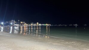 A nighttime beach scene with calm waters reflecting city lights. - Cozzy Seaview Apartment (Ho Chi Minh City)