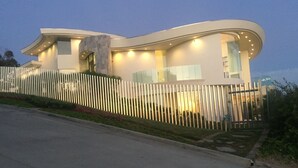 A modern, curved building with a white fence and a well-lit entrance. - Magnificent ocean view luxury mansion in La Jolla, California. Pool and Spa (San Diego)