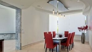 A dining area with a round table and red chairs, a vase with red flowers, and a modern ceiling design. - Magnificent ocean view luxury mansion in La Jolla, California. Pool and Spa (San Diego)