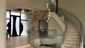 A modern interior with a curved staircase, glass railings, and a stone wall. - Magnificent ocean view luxury mansion in La Jolla, California. Pool and Spa (San Diego)