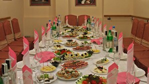 A conference room with a long table set for a meal, surrounded by red chairs, with framed pictures on the walls. - Hotel Ekran (Lviv)