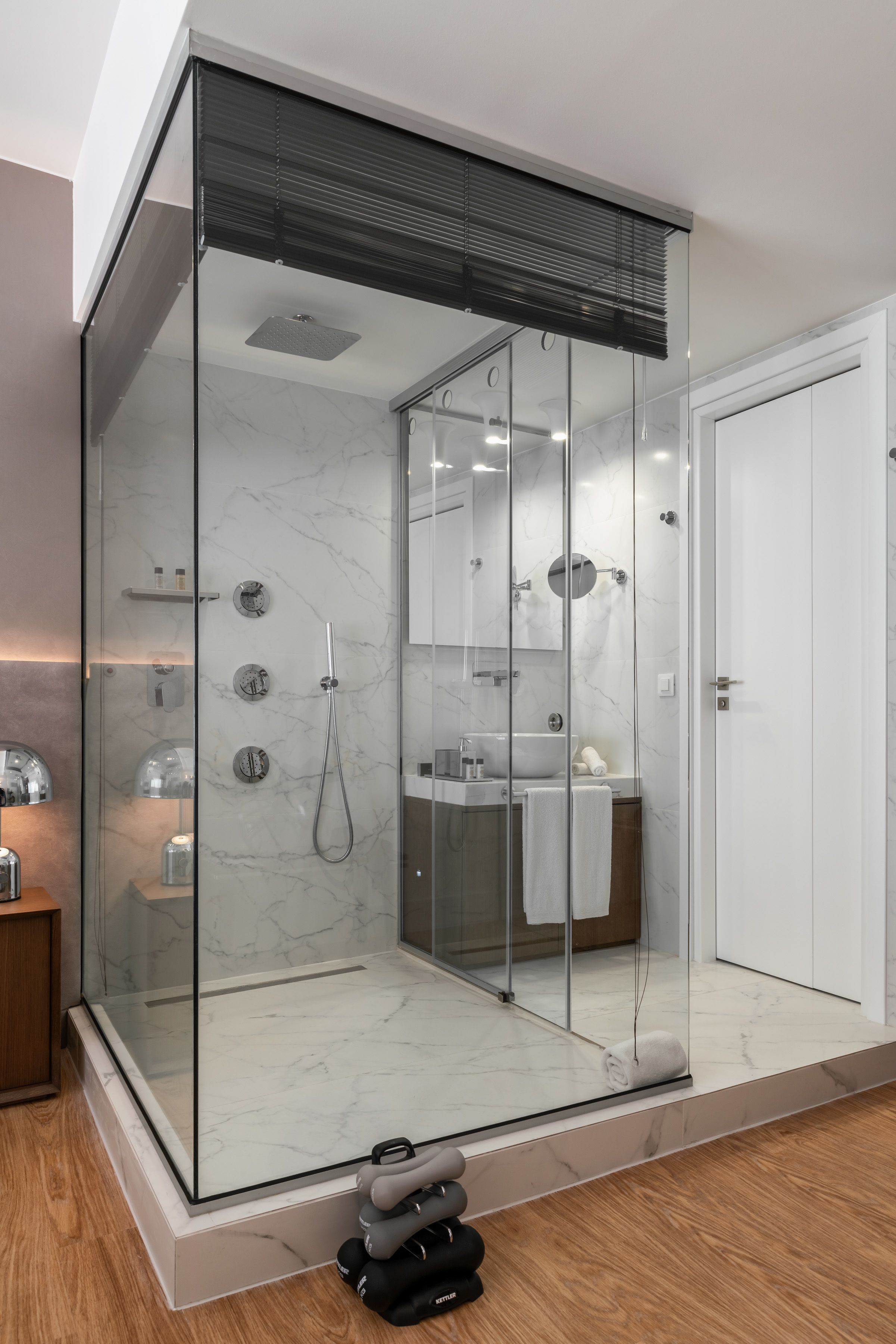 Une salle de bain moderne avec une douche à parois de verre, un lavabo blanc et un miroir au-dessus du lavabo.