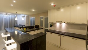A modern kitchen with white cabinets, a black countertop, and pendant lighting. - Cozzy and Beauty Apartment (Ho Chi Minh City)