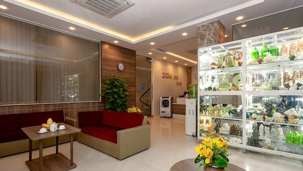 Eine Hotelhalle mit einer Rezeption, einem roten Sofa, einem kleinen Tisch mit Teekannen, einer Uhr und einer Auswahl an Souvenirs.