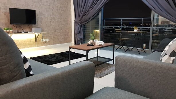 A modern living room with grey sofas, a coffee table, and a TV on the wall.