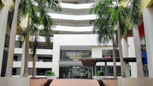 A multi-level building with a central atrium, palm trees, and a modern architectural design.