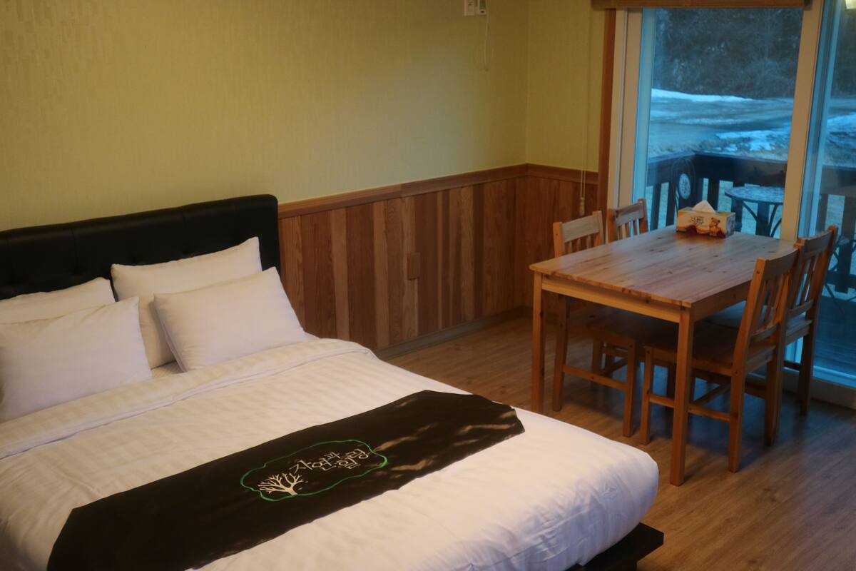 A hotel room with a bed, a wooden table, and chairs.