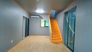 Un pasillo con una escalera de madera, una ventana pequeña y una puerta.