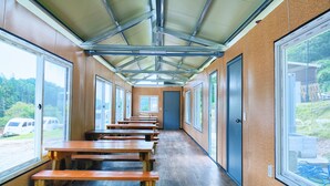 Un largo pasillo con bancos de madera, ventanas amplias y una estructura de techo metálico.