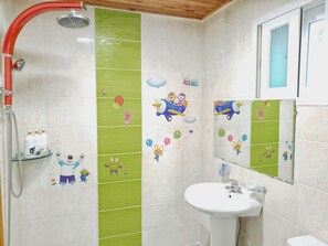 Bathroom features a shower, sink, and green-tiled wall with cartoon characters.