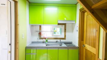 A kitchen with green cabinets, a stainless steel sink, and wooden accents.