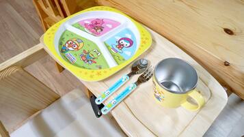 A wooden table with a yellow tray, a mug, and a fork with a cartoon design.