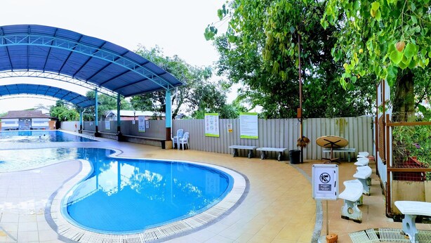 An indoor swimming pool with a covered area, tiled flooring, and potted plants. - Hotel ASRC (Alor Setar)