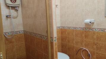 A bathroom with a shower, toilet, and a water heater.