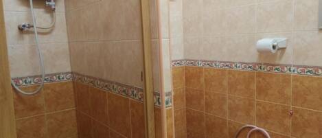 A bathroom with a shower, toilet, and a water heater.