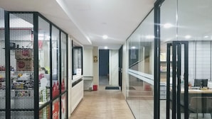A modern office interior with glass partitions, a reception desk, and a wooden floor. - Hotel ASRC (Alor Setar)