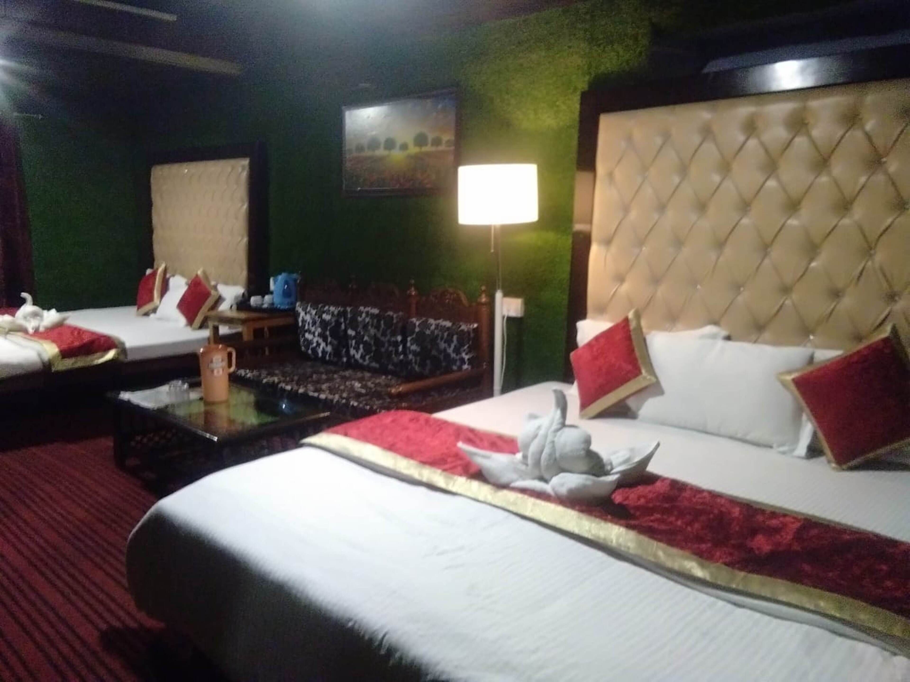 A hotel room with two beds, a large window, a green wall, and a chandelier.