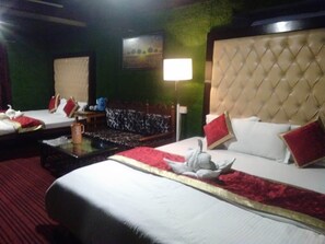 A hotel room with two beds, a large window, a green wall, and a chandelier. - Hotel Kausani Retreat (Somashwar)