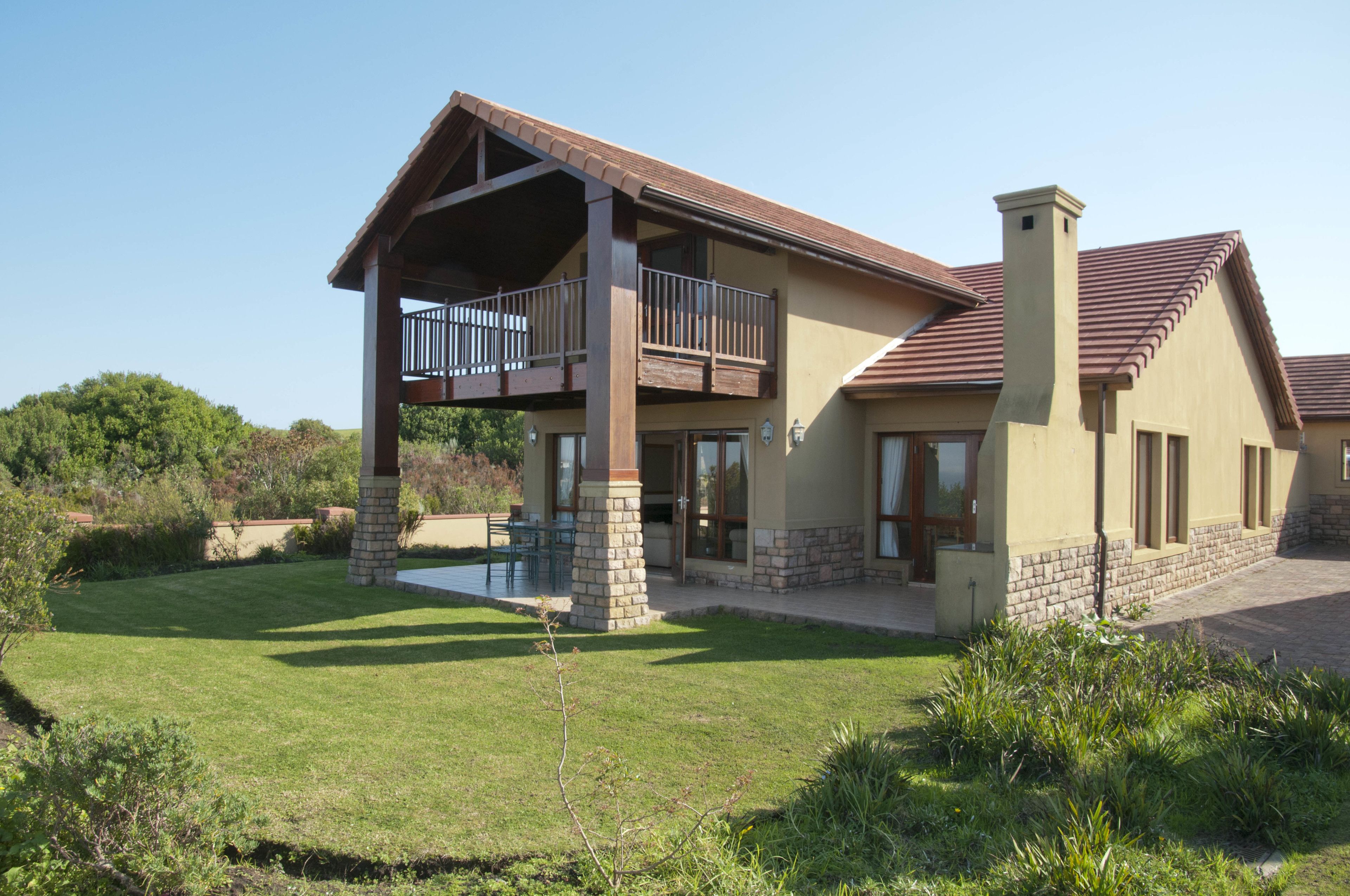 Ein zweistöckiges Haus mit Balkon, Schornstein und gepflegtem Rasen.