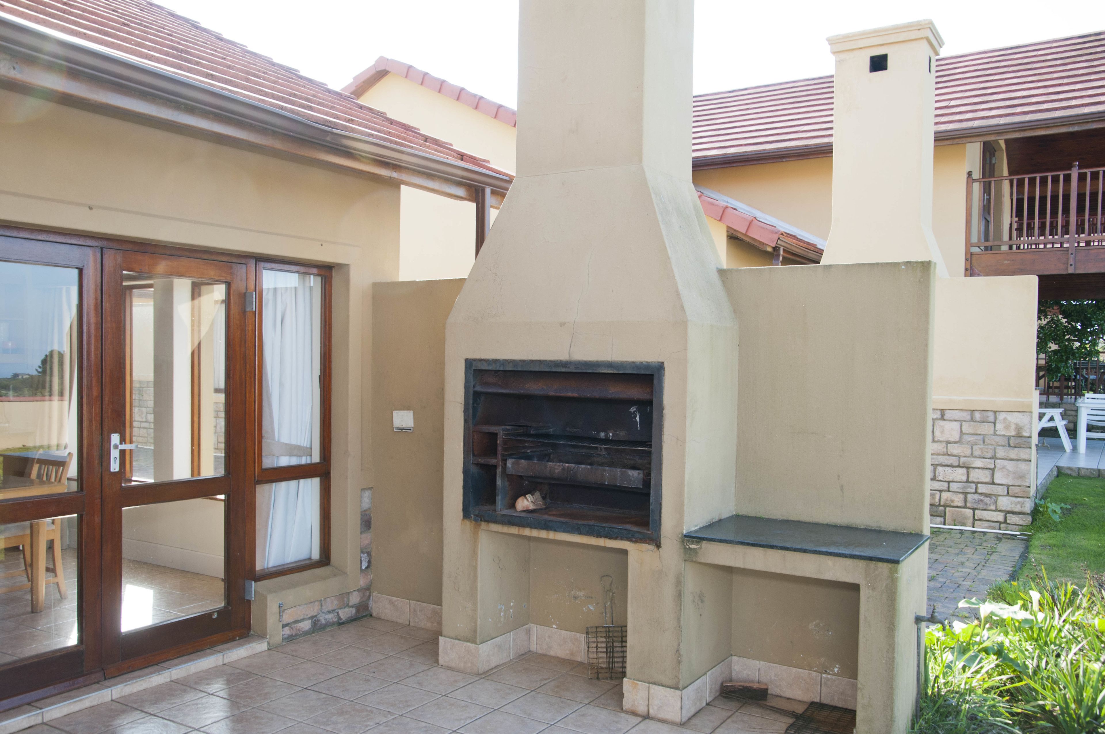 A patio area with a built-in oven, a sliding glass door, and a stone wall.