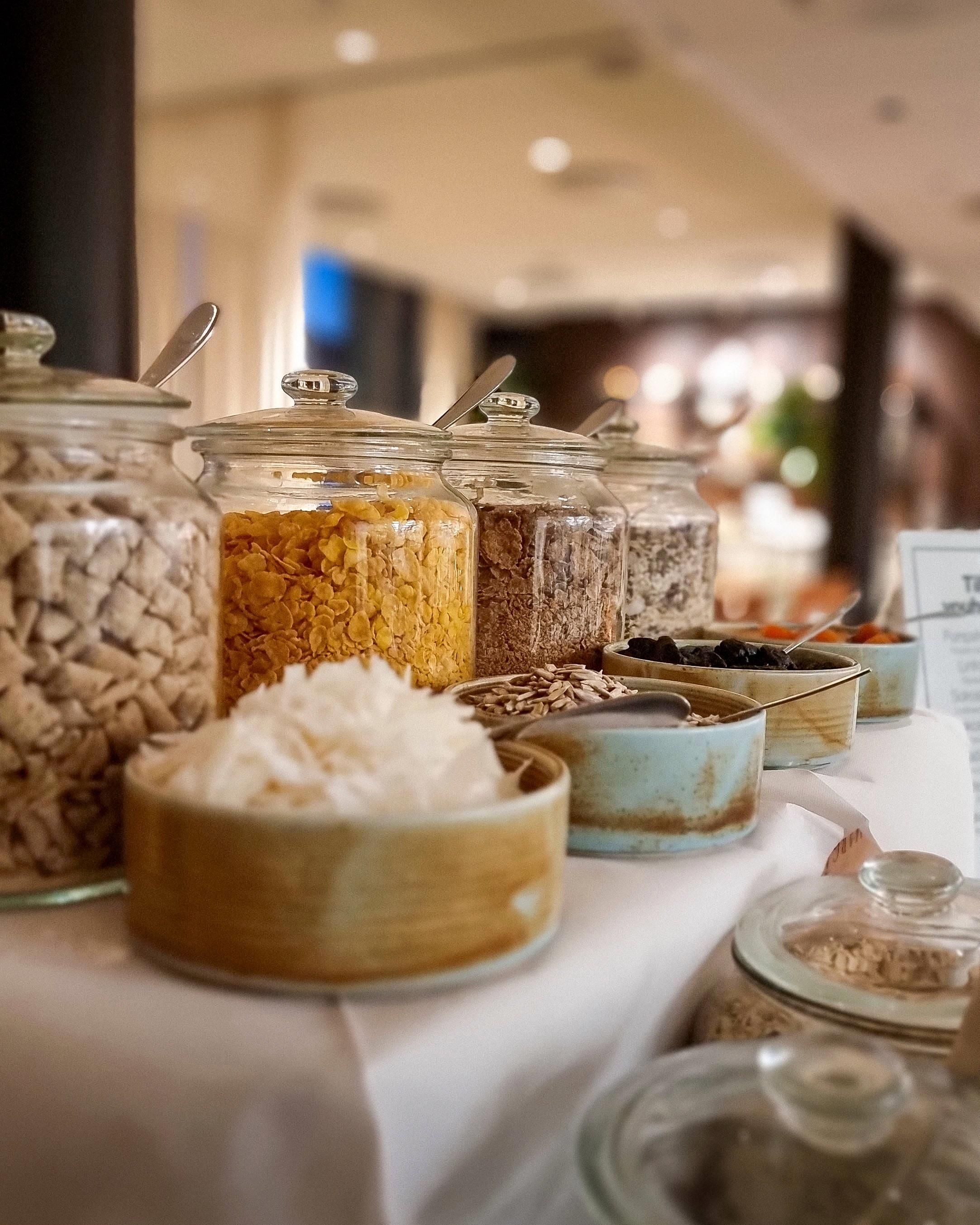 A buffet table with various food items in glass containers, including cereals and grains.
