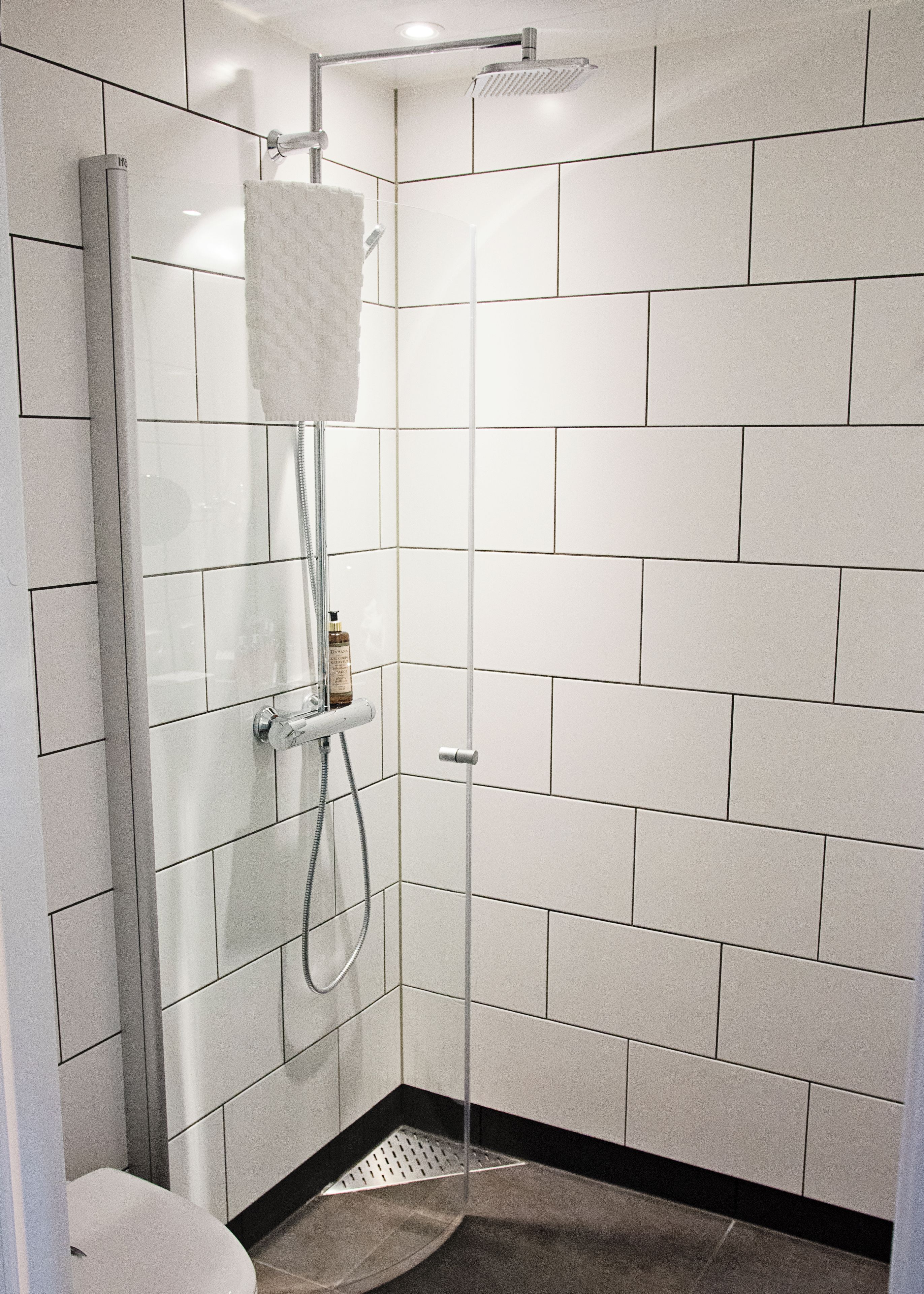 A modern shower with a glass enclosure, a handheld showerhead, and a wall-mounted faucet.