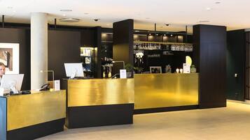 Un espace d’accueil comprenant un comptoir, un ordinateur et un coin bar avec des verres.