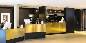 A reception area with a counter, a computer, and a bar area with glasses. - Quality Hotel Öresund (Landskrona)