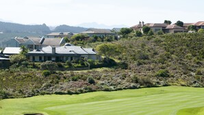 A golf course with a well-maintained green, a walking path, and a residential area with houses and trees in the background. - Villa 5 (Knysna)