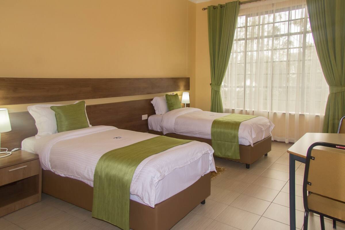 Ein Hotelzimmer mit zwei Betten, einem Schreibtisch und einem Stuhl.
