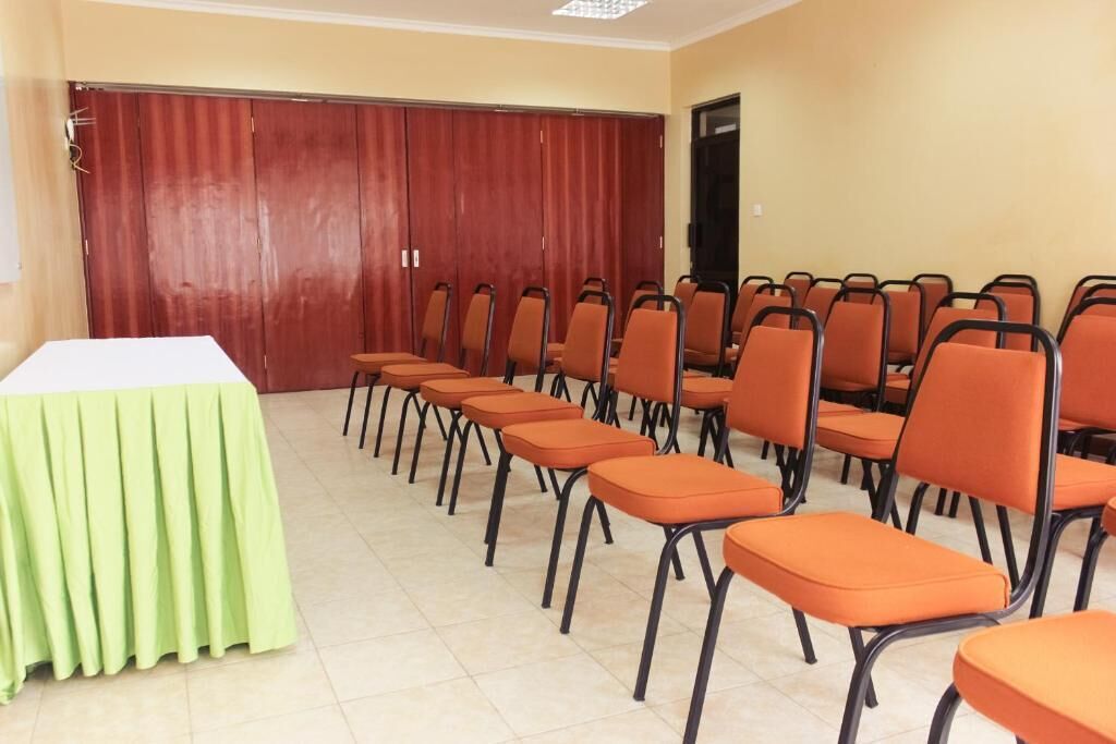 A conference room with a long table and rows of orange chairs.